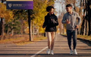 A young couple wearing warm clothes runs in a park for mental health and wellbeing as a new year goal.