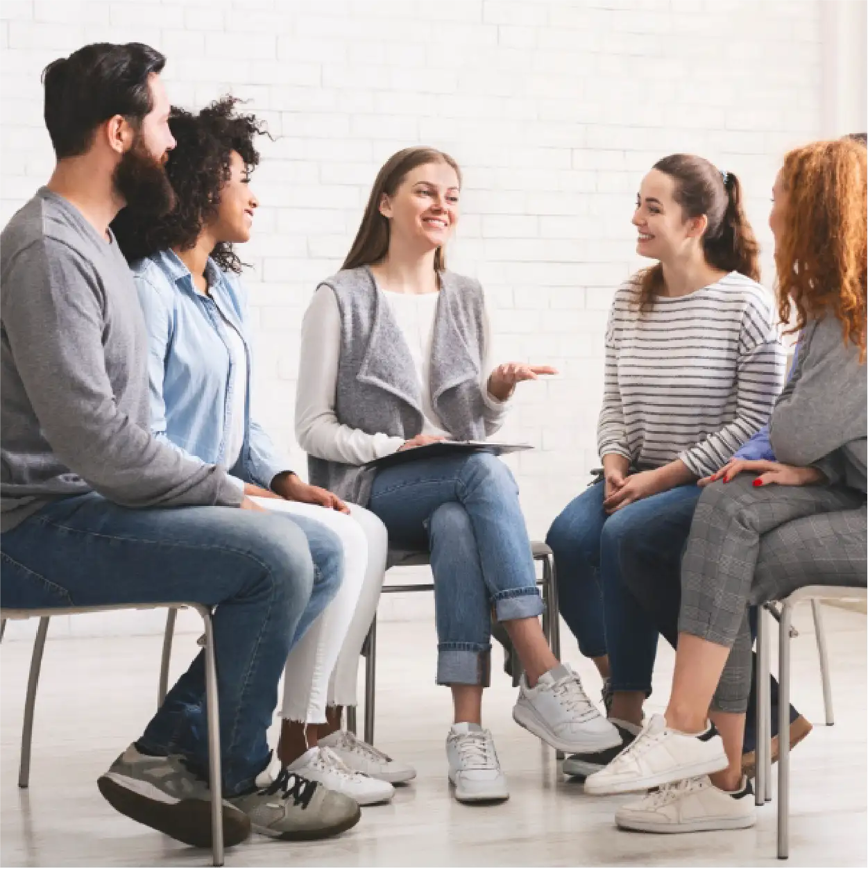 5 young adults sit in a circle while in group therapy.