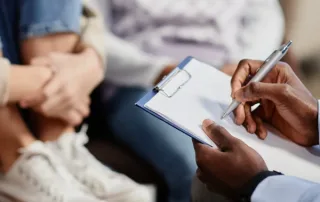 A professional therapist writes on his clipboard during a therapy session.
