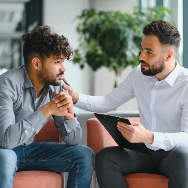 A professional therapist talks to a young man in therapy.