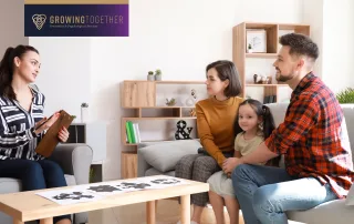 A family therapy session with a psychologist talking to a couple and their young daughter, highlighting open communication and connection in a supportive setting. The Growing Together logo is displayed in the corner.