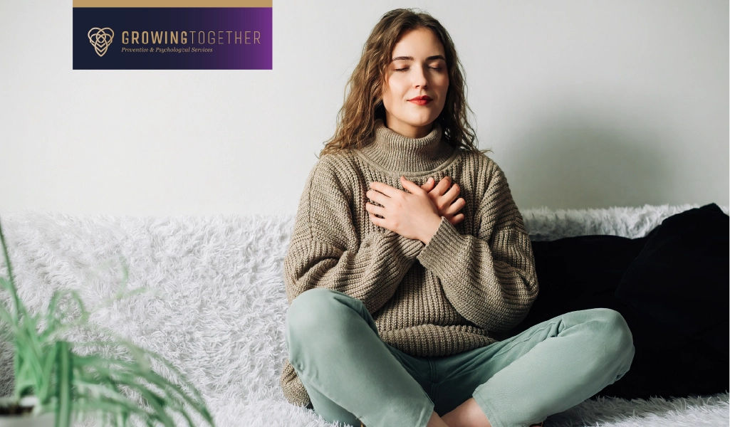 A woman sitting cross legged on a couch while taking deep breaths.
