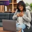 A woman sits in front of a laptop while attending online therapy.