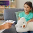 Little smiling girl with stuffed animal talking to child psychologist during therapy session in office.